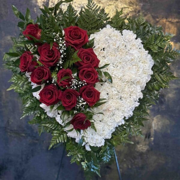 White carnation funeral heart with red roses and greenery in Naples Florida.
