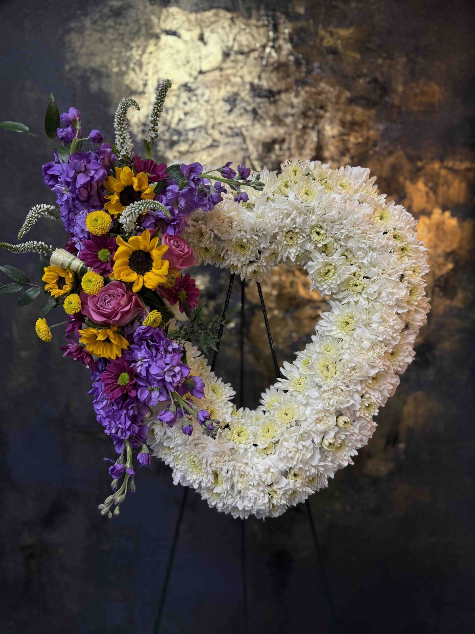 Open Heart Funeral Spray close up Colorful open heart funeral spray with white flowers, sunflowers, purple stock and pink roses in Naples Florida.