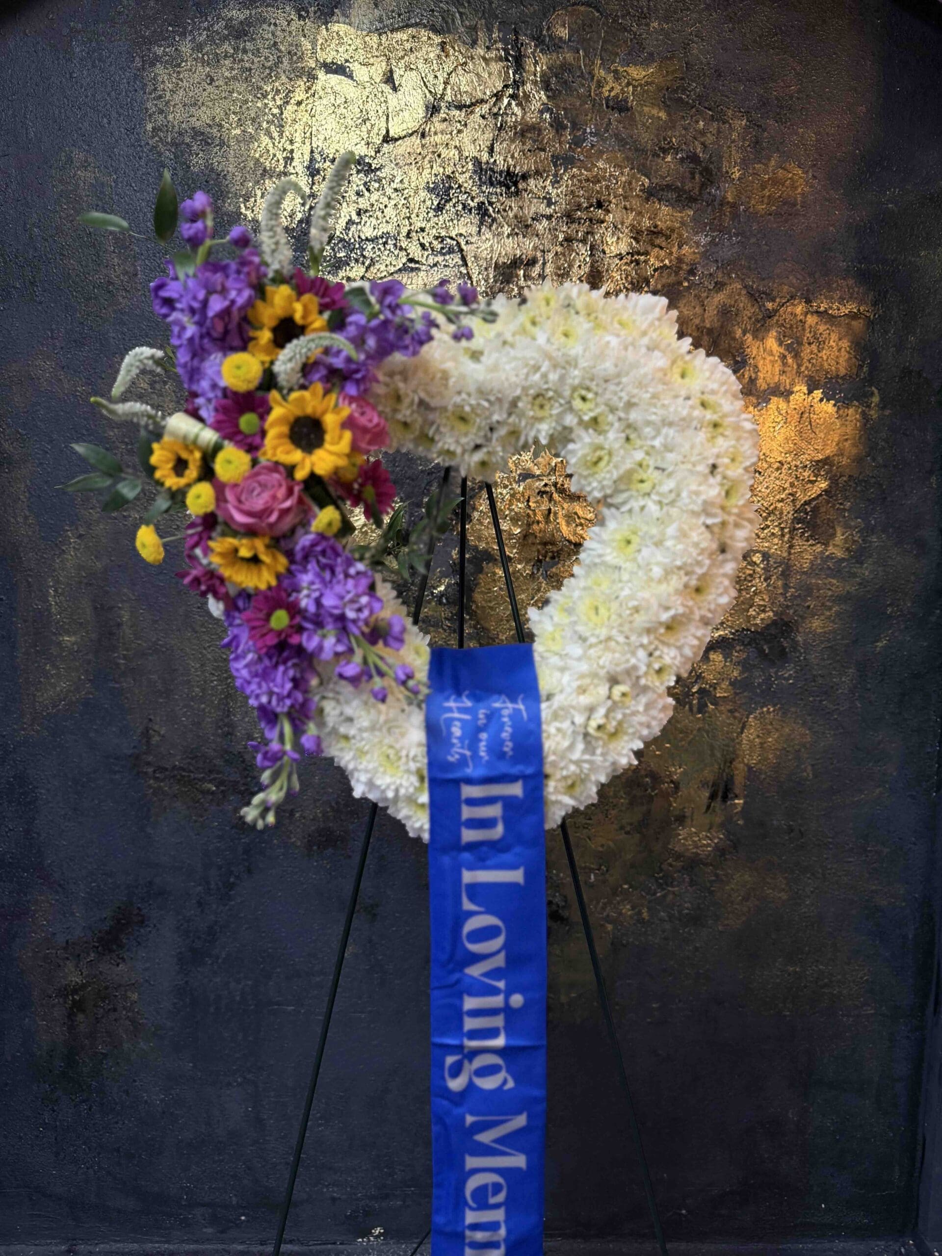 Open Heart Funeral Spray Colorful open heart funeral spray with white flowers, sunflowers, purple stock and pink roses in Naples Florida.